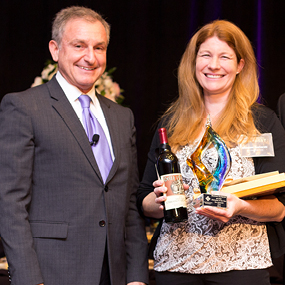 Shannon Kucharski from San Clemente Cove stands on stage with David Brown, holding her Best of the Best award.