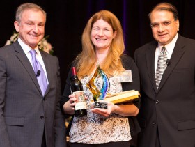Shannon Kucharski from San Clemente Cove receives her award on stage with David Brown and Nigel Lobo
