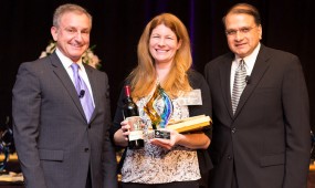 Shannon Kucharski from San Clemente Cove receives her award on stage with David Brown and Nigel Lobo