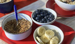 red white and blue colored flatware with bowls of oats, blueberries and sliced bananas