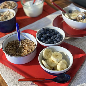 red white and blue colored flatware with bowls of oats, blueberries and sliced bananas